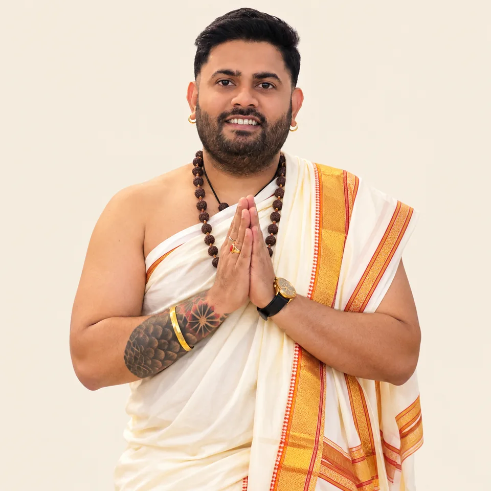 Pandit Ankush Ji in traditional white clothing with hands joined in namaste